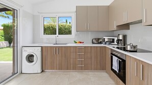 Une cuisine moderne équipée d’un lave-linge, d’un four à micro-ondes et d’un four traditionnel.