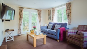 A living room with a blue sofa, a plaid armchair, a wooden coffee table, and a TV mounted on the wall.