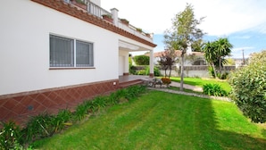 Ein zweigeschossiges Haus mit weißer Fassade, einem Ziegeldach und einer kleinen Veranda.