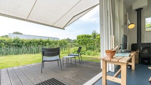 Eine Terrasse mit zwei Stühlen, einem Tisch, einem Fernseher und einem Kamin.