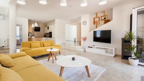 A modern living room with a yellow sofa, a white coffee table, and a flat-screen TV. - Villa Anfiteatro Adriatico with Pool (Murter)