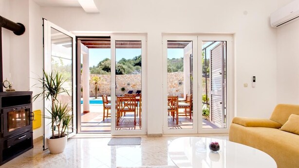 A modern living room with a fireplace, a sofa, and a glass coffee table. - Villa Anfiteatro Adriatico with Pool (Murter)