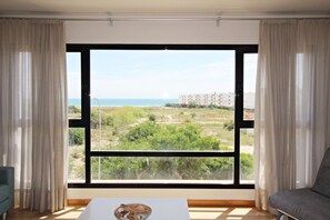 A room with a large window, a bed, a bedside table, and a chair.