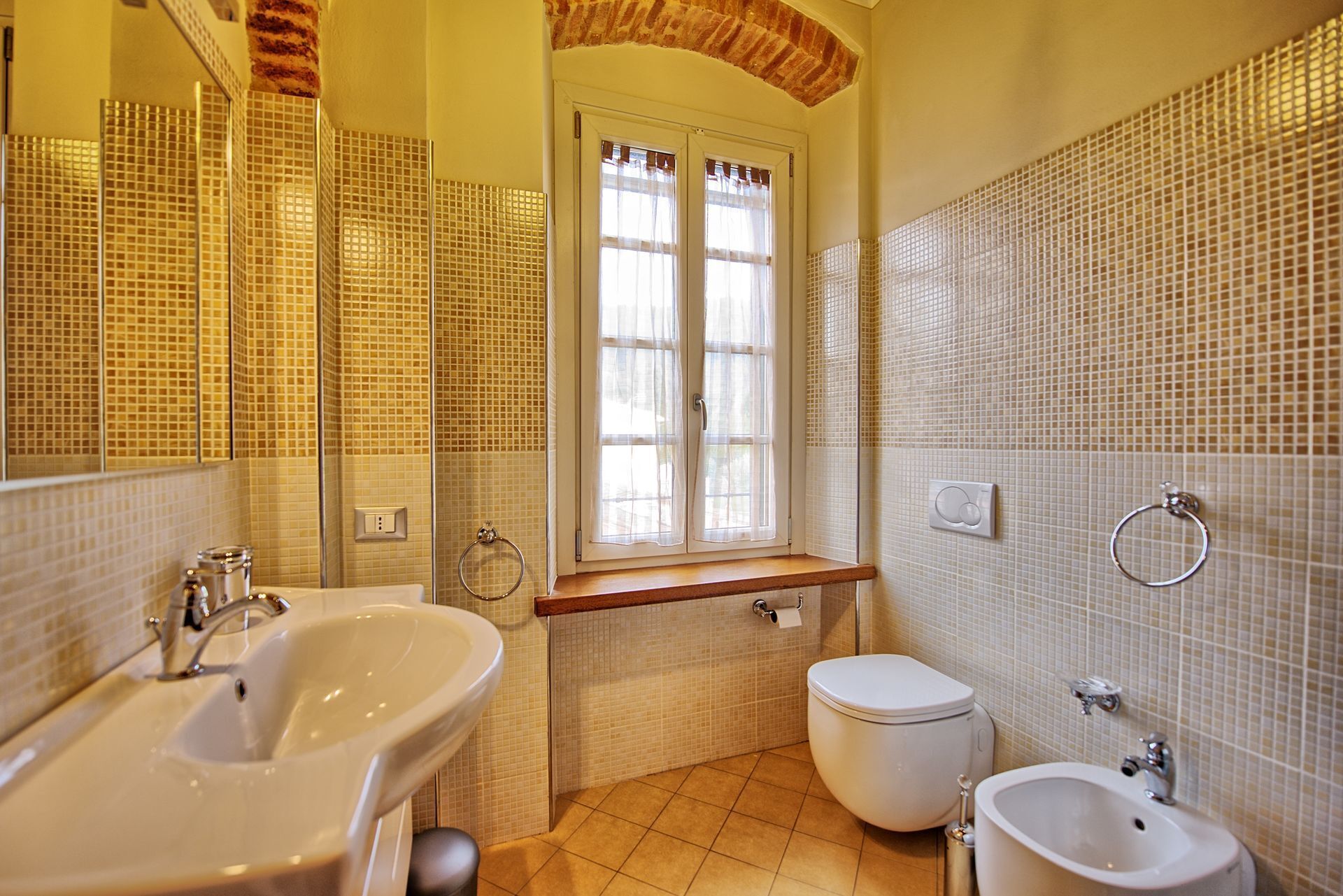 Une salle de bain avec un grand miroir, un lavabo, des toilettes et un bidet.
