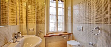 Une salle de bain avec un grand miroir, un lavabo, des toilettes et un bidet.