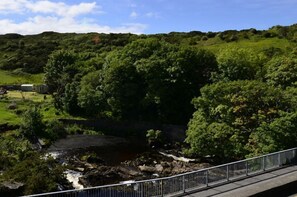 A bridge over a river with lush greenery and hills in the background. - Cottage 173 - Clifden (Clifden)