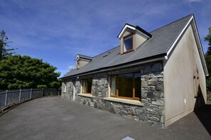 A stone house with a sloped roof, a small attic window, and a large front window. - Cottage 173 - Clifden (Clifden)