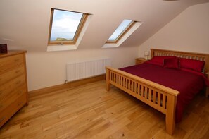 Un dormitorio con cama de madera, cómoda, radiador y tragaluces.