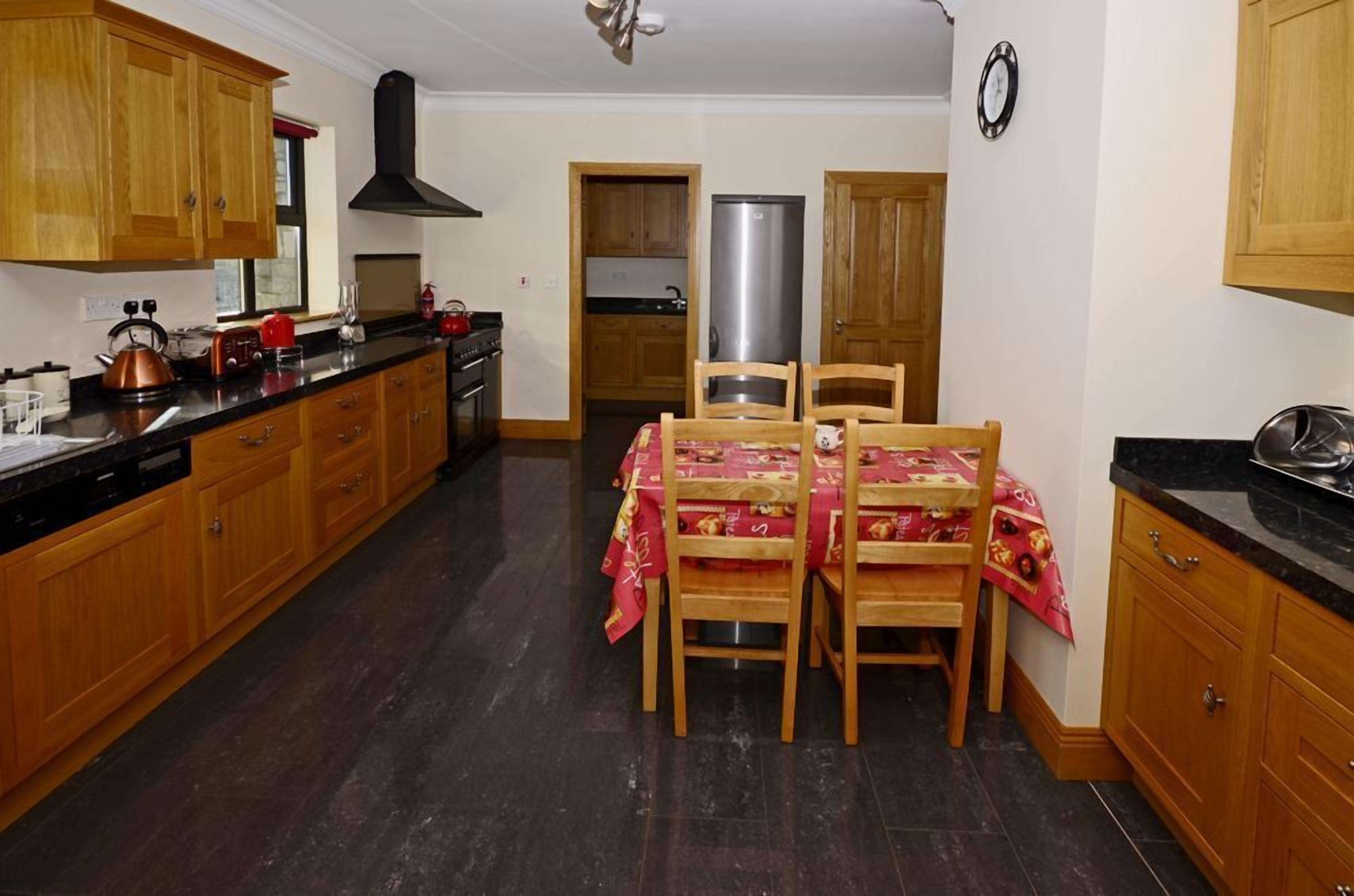 A kitchen with wooden cabinets, a stainless steel refrigerator, and a dining table set for four.