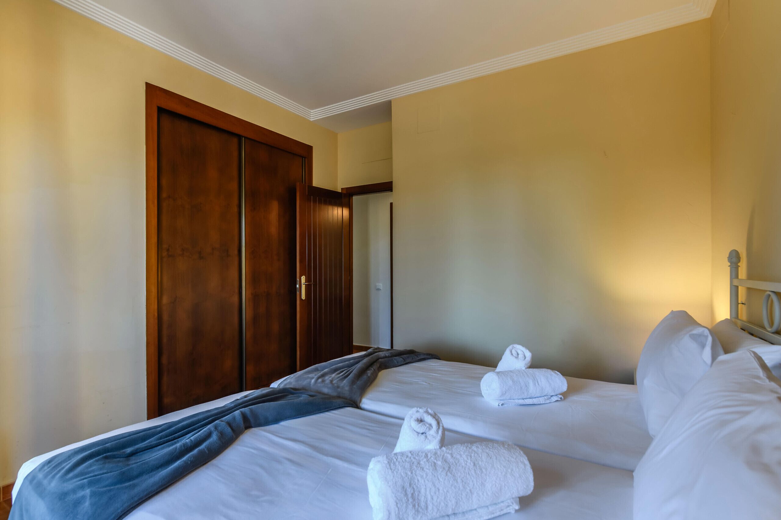 A hotel room with two beds, a wooden wardrobe, and a door.