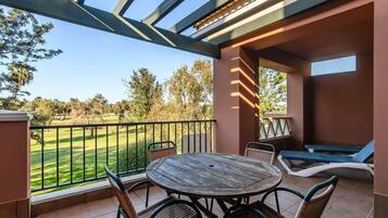 Une terrasse couverte avec une table ronde en bois et des chaises, une petite table de billard et des fauteuils de relaxation.