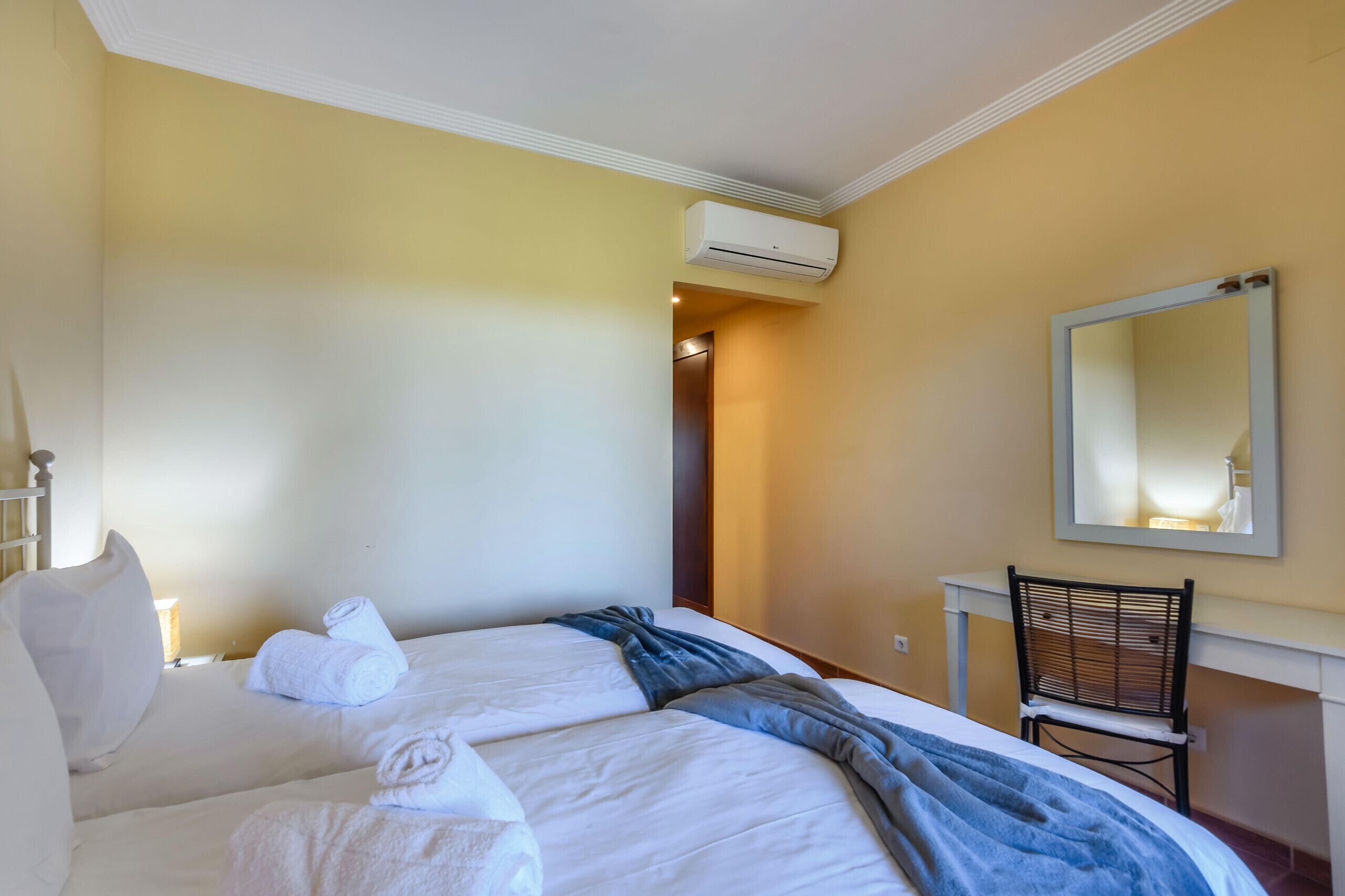 Een hotelkamer met een bed, een stoel, een spiegel en een airconditioning.