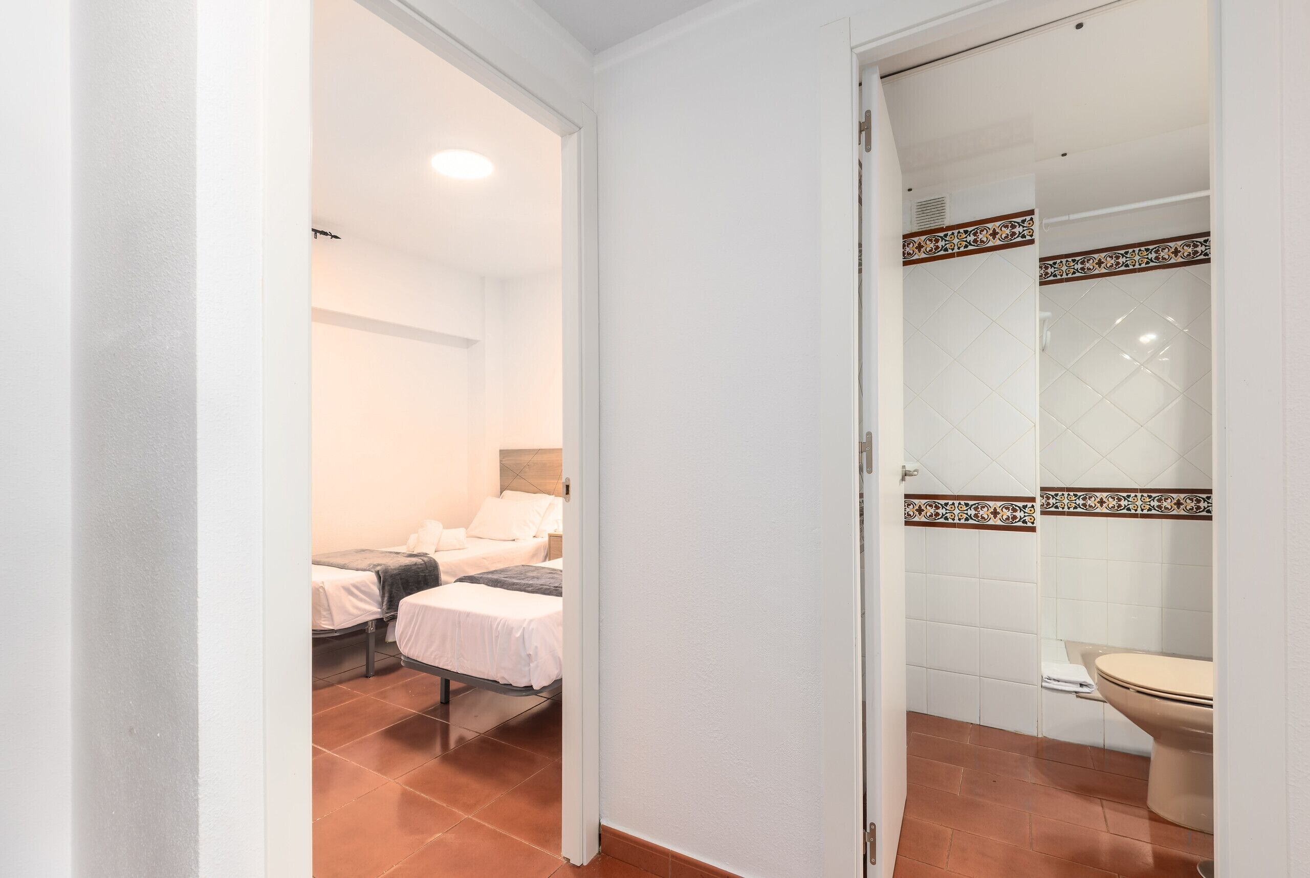 A hotel room with a bed, a bedside table, and a bathroom with a toilet and shower.