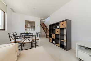Un salon moderne comprenant un coin repas, un escalier et des éléments de rangement intégrés.