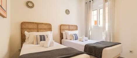 Habitación de hotel con dos camas, una ventana con cortinas y dos placas decorativas en la pared.