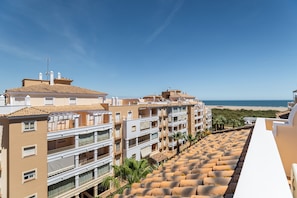 A multi-story building with balconies, a beach view, and a clear sky.
