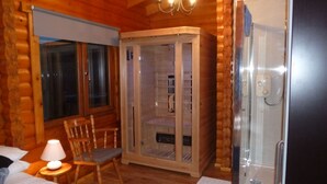 A cozy log cabin room with a bed, a wooden cabinet, a chair, and a shower area. - Log Cabin with Hot Tub for 2 | In the Cairngorm National Park | Accepts Dogs (Spittal of Glenshee)