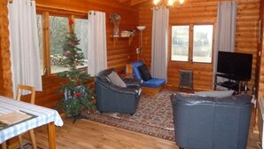 A cozy log cabin interior with a fireplace, a television, and a Christmas tree. - Log Cabin with Hot Tub for 2 | In the Cairngorm National Park | Accepts Dogs (Spittal of Glenshee)