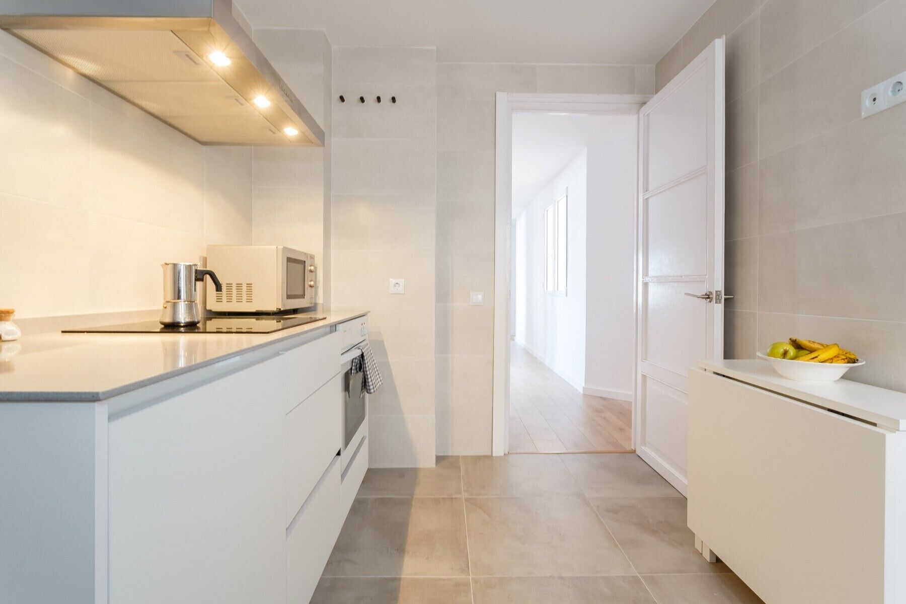 Una cocina moderna con armarios blancos, un microondas y un lavamanos.
