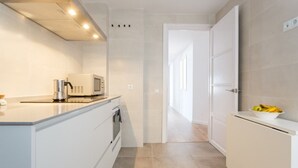 Een moderne keuken met witte kasten, een magnetron en een spoelbak.