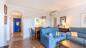 Ein Wohnzimmer mit einem blauen Sofa, einem Holztisch und einem Essbereich mit Tisch und Stühlen.