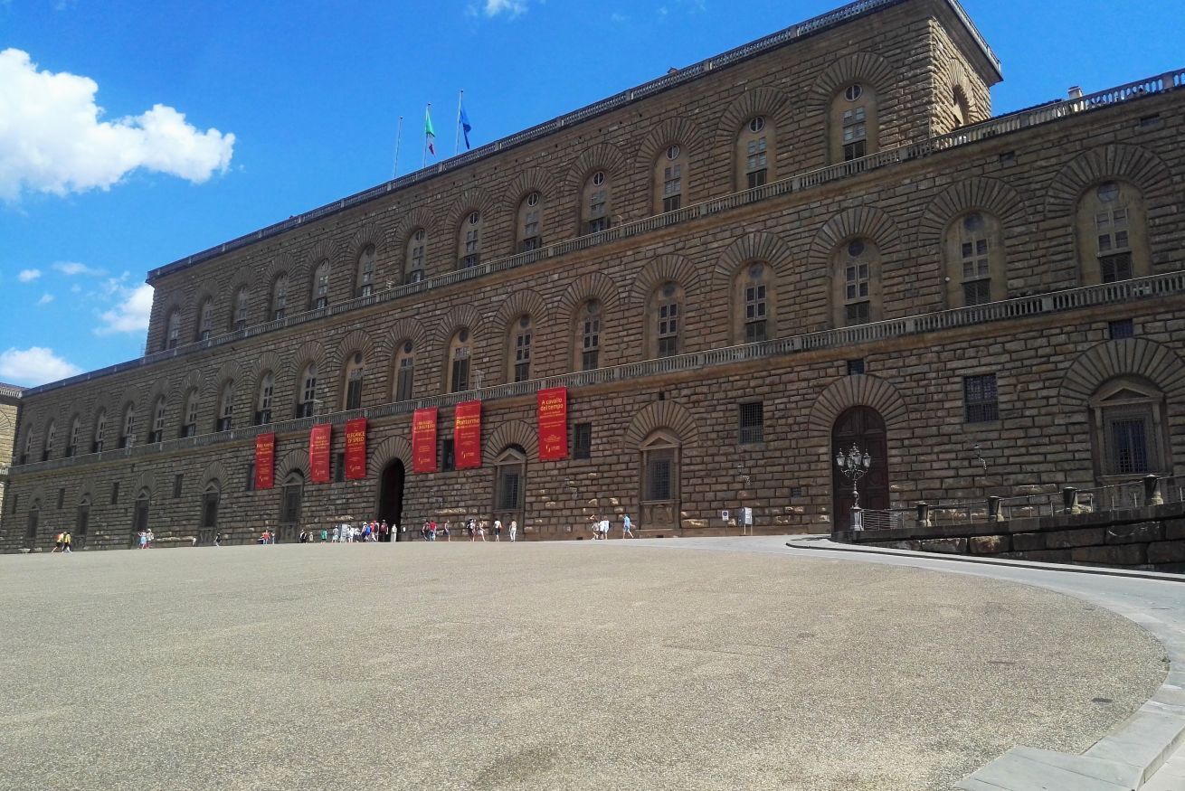 A large stone building with multiple arched windows and a central courtyard.