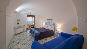 A room with a bed, a chair, a small table, and a view of the sea. - Casa Sunset - Panoramic terrace overlooking Positano and Capri (Praiano)