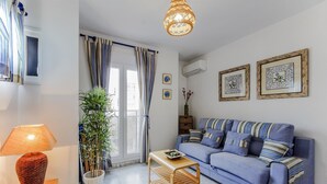Un salón con sofá, lámpara, planta y cuadros en la pared.