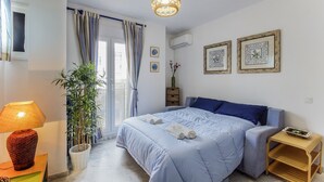 Un dormitorio con cama, mesita de noche, lámpara, planta en maceta y lámpara colgante.