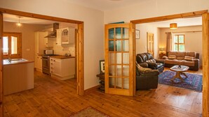 Amplia sala de estar con piso de madera, un sofá, una mesa de centro y una cocina al fondo.