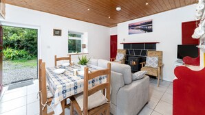 A cozy living room with a fireplace, a dining area with a table and chairs, and a sofa. - Cottage 194 - Leenane - sleeps 4 guests  in 2 bedrooms (Leenane)