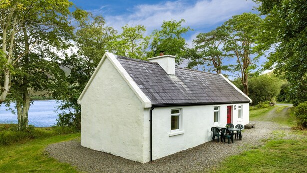 A small white cottage with a grey roof, a red door, and a gravel driveway. - Cottage 194 - Leenane - sleeps 4 guests  in 2 bedrooms (Leenane)