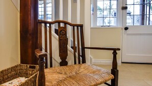 A wooden chair with a woven seat and backrest, positioned in front of a white door with a window above it. - A sudeley castle cottage that sleeps 4 guests  in 2 bedrooms (Winchcombe)