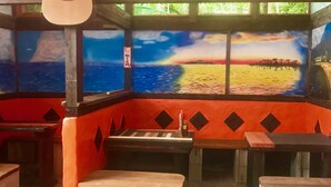Un restaurante con un mural de temática náutica en la pared, mesas de madera y una decoración en colores rojo y negro.