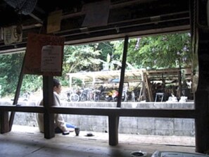 A room with a large window, a wooden table, and a sign on the wall. - Gekkousou Okinawa - Hostel (Naha)