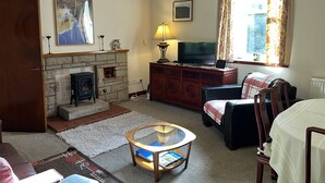 A living room with a fireplace, television, and a cozy seating area. - The Maid's House, Carmichael Country Cottages. 4 star comfortable cottage on rural Estate (Biggar)