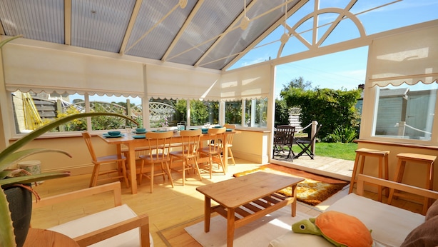 A conservatory with wooden furniture, a turtle plush toy, and a view of the garden. - 4 Brooks Close -  a house that sleeps 6 guests  in 3 bedrooms (Bembridge)