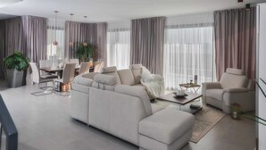 A modern living room with a sofa, armchairs, and a dining area.