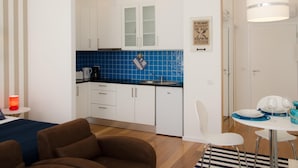A modern kitchen with white cabinets, blue tiles, and a dining area with a table set for two. - Porto Náutico & Spa 3 | Studio Deluxe (Porto)