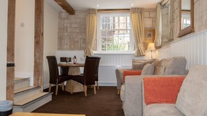 Ein gemütliches Zimmer mit Esstisch, Stühlen, einer Couch und einer Treppe.