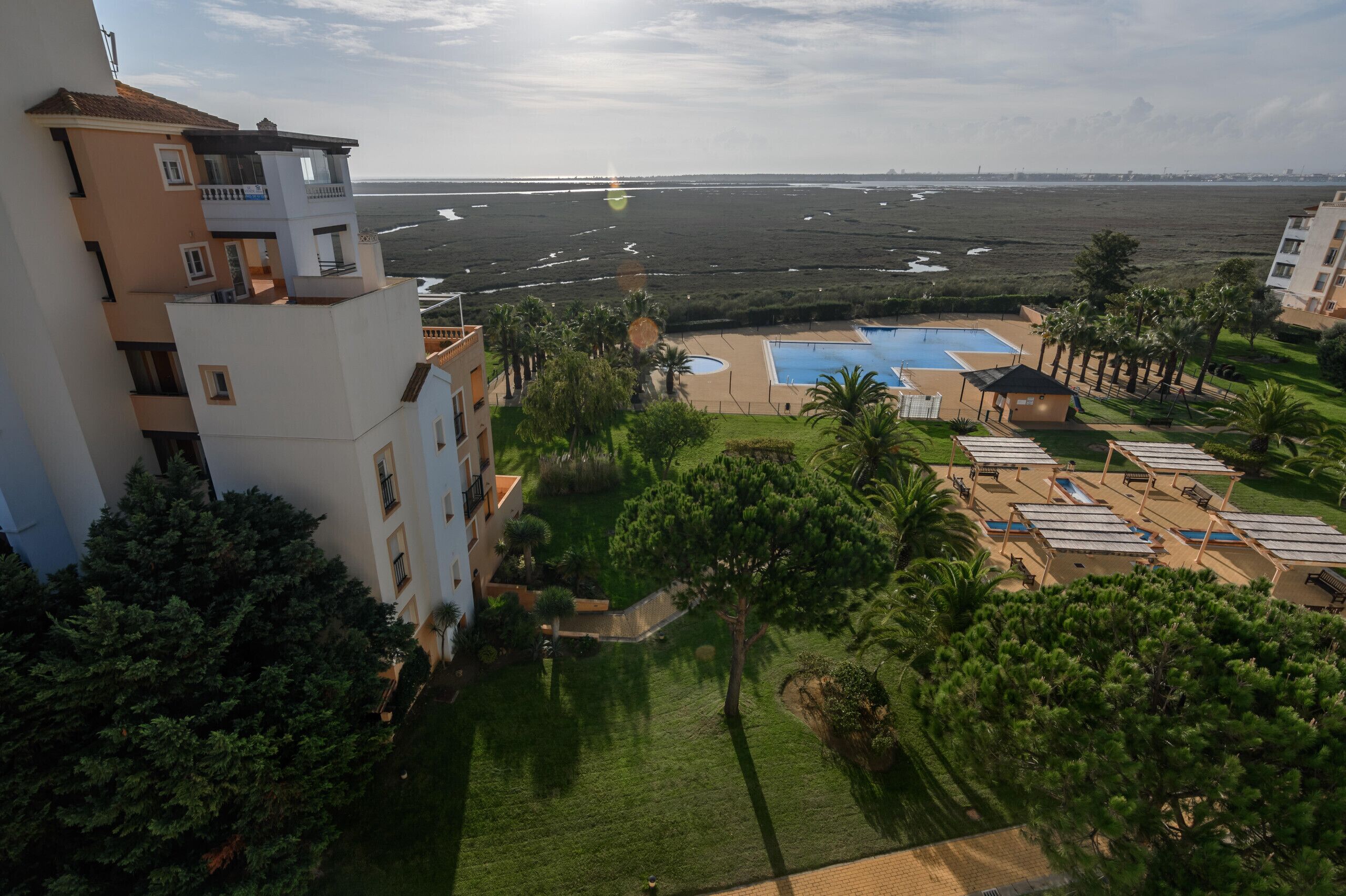 Un resort con piscina, tumbonas y vista al mar.