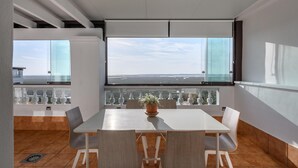 A modern dining area with a large table, white chairs, and a potted plant.