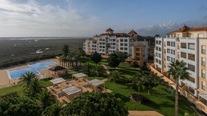 A resort with multiple buildings, a swimming pool, and a beach view.