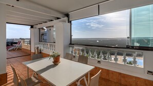 A modern room with a large window offering a view of the beach and cityscape.