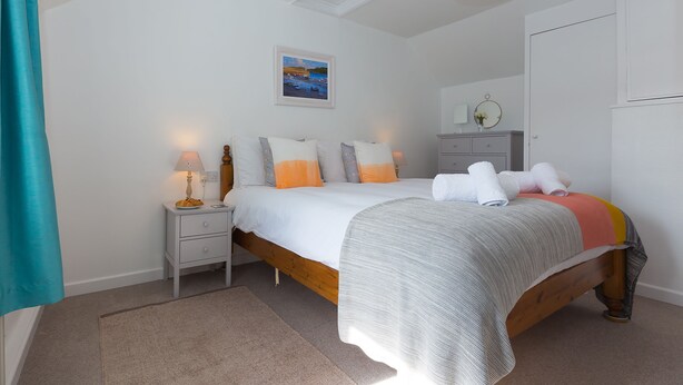 Une chambre à coucher avec un lit, des tables de chevet, une commode, un tableau et un miroir.