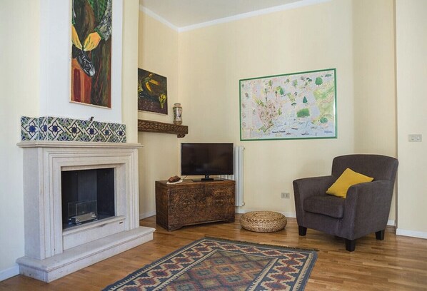 A living room with a fireplace, a television on a wooden cabinet, a map on the wall, and a patterned rug. - Kalsa Casa di Charme con Terrazza by Wonderful Italy (Palermo)