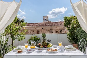 An outdoor dining table set with breakfast items, a pitcher, and a view of a historic building with a bell tower. - Kalsa Casa di Charme con Terrazza by Wonderful Italy (Palermo)