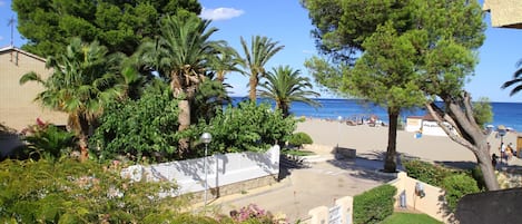 A coastal view with a beach, palm trees, and a clear sky.