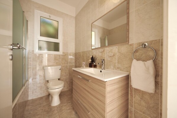 A modern bathroom with a toilet, sink, and mirror.