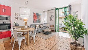 Una sala moderna con comedor, cocina y un balcón con plantas.